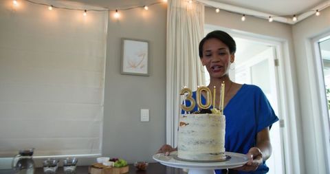 Woman Presenting Birthday Cake with Sparkling Candles in Living Room Celebration
