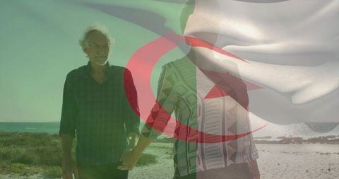 Senior couple walking hand in hand on beach with faint algerian flag overlay
