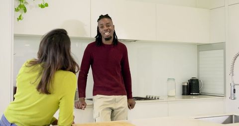 African American man and Indian woman chatting in modern minimalist kitchen, cozy home lifestyle