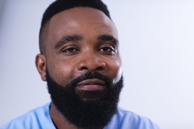 Portrait of smiling, bearded african american male doctor in hospital corridor. Medical services, hospital and healthcare concept.