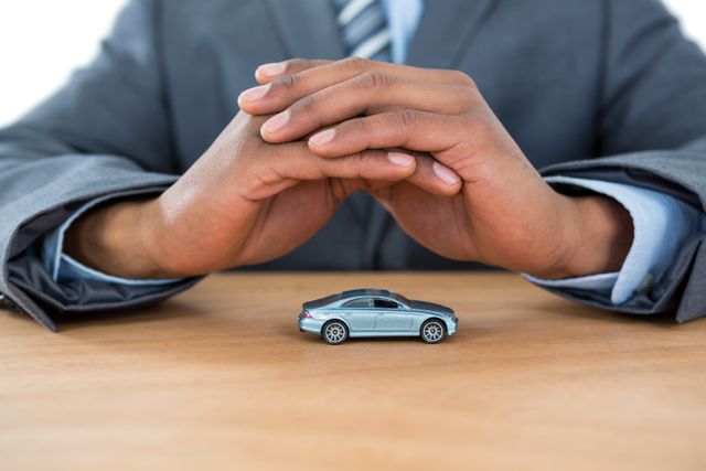 Close-up of businessman protecting toy car with hands
