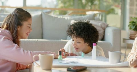 Friends painting nails at home during cozy sunlit living room manicure gathering