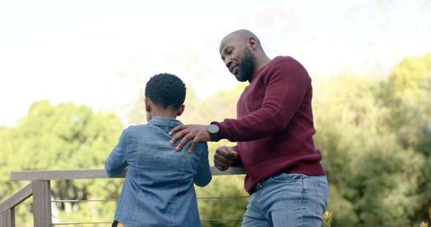 African american father and son sharing quiet moment on deck overlooking greenery