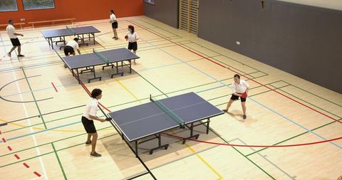 Table tennis team practicing at sports hall, athletic training