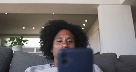Relaxing man scrolling smartphone on gray couch in modern minimalist living room interior