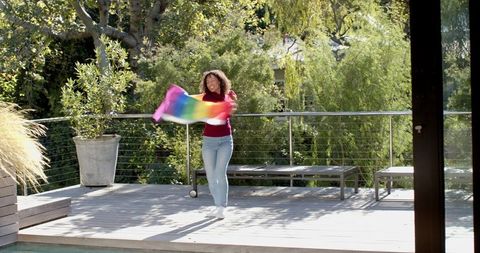 African american woman waving rainbow fabric outdoors