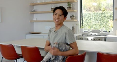 Smiling Man Holding Cozy Blanket in Minimalist Kitchen
