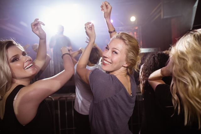 Young women dancing and enjoying themselves at a lively nightclub party. Ideal for use in promotions for nightlife events, music festivals, social gatherings, and entertainment venues. Perfect for illustrating concepts of fun, friendship, and youthful energy.