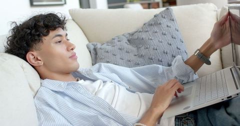 Young Adult Relaxing on Couch Using Laptop with Smartwatch