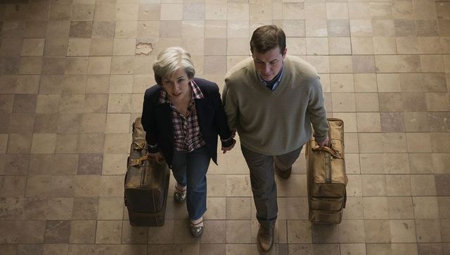 Mature couple walking with vintage leather suitcases across worn tiled concourse evoking nostalgia