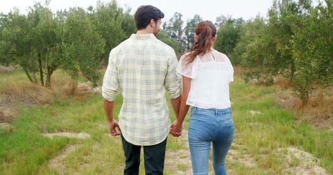 Couple walking hand in hand through serene field