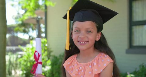 African american girl celebrating graduation holding diploma wearing mortarboard and tassel