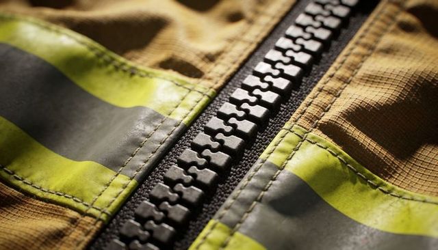 Molded zipper close-up on high-visibility protective jacket with stitched reflective tape