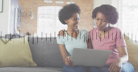 Mother and daughter collaborating on homework using laptop with animated charts overlay