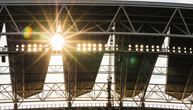 Stadium roof trusses featuring sunburst lens flare, floodlights and industrial steelwork