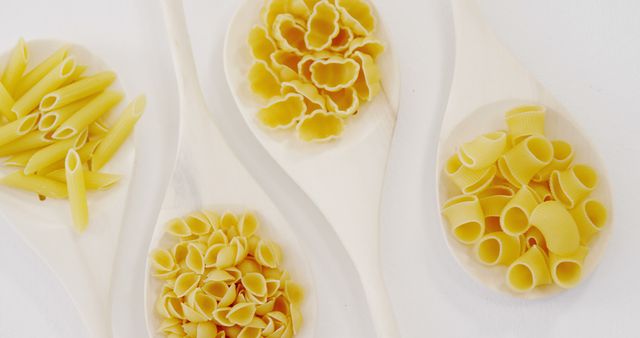 Assorted Uncooked Pasta on Wooden Spoons on White Background - Download Free Stock Images Pikwizard.com