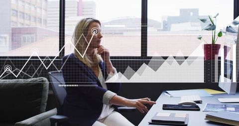 Mature businesswoman analyzing data on desktop with analytics charts overlay