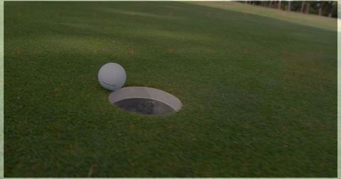Golf ball balance on hole rising tension sports moment on putting green