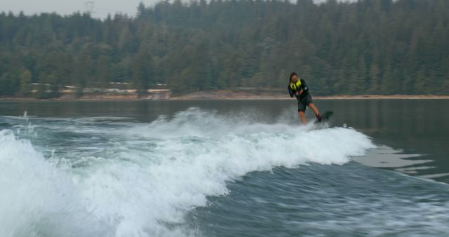 Man Wakeboarding on Lake Surrounded by Forested Hills - Download Free Stock Images Pikwizard.com