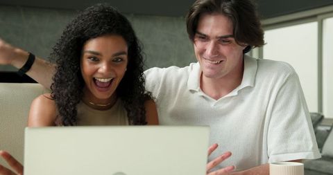 Happy couple enjoying online content together in living room