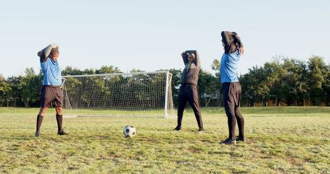 Soccer players stretching on field for team warm-up routine