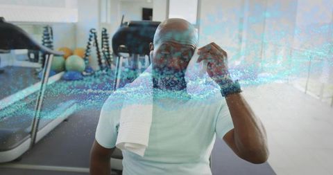 Physically fit mature man wiping forehead in gym environment