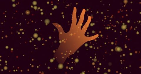 Silhouette of hand with glowing particles on black background