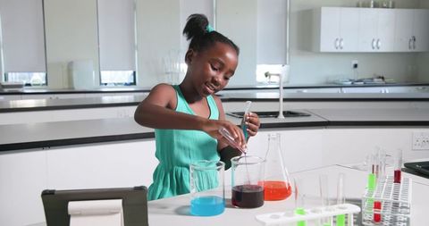 African teen girl conducting colorful chemistry experiment in modern school lab