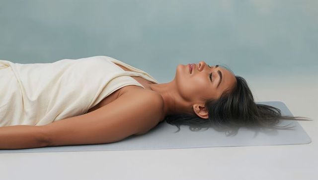 Serene asian woman relaxing on yoga mat in wellness studio wrapped in cream wrap