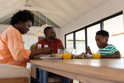 African american family sharing breakfast at modern dining table with orange juice