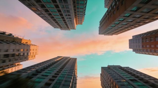 High-rise towers framing vibrant teal and peach sunset sky drawing eye upward