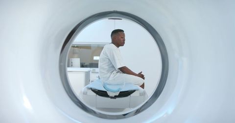 African american man sitting inside mri gantry awaiting diagnostic scan in radiology