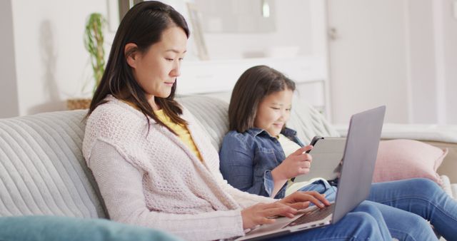 Mother and Daughter Using Laptop and Smartphone Together on Sofa - Download Free Stock Images Pikwizard.com