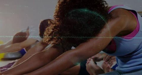 Group yoga class stretching forward fold close-up emphasizing flexibility and focus