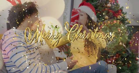 Couple Sharing Cozy Christmas Moment on Couch with Santa Hat, Tree and Gold Confetti