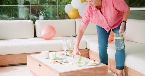 Senior Lesbian Couple Cleaning Post-Party with Balloons and Drinks