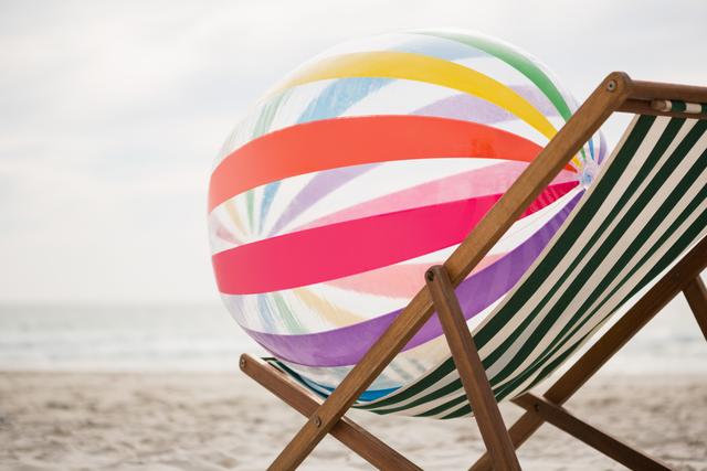 Striped beach ball kept on empty beach chair at tropical sand beach