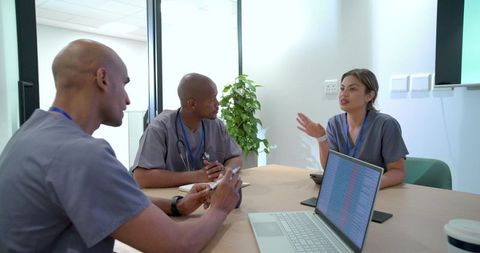 Diverse healthcare team collaborating in clinic meeting reviewing patient data and care plans