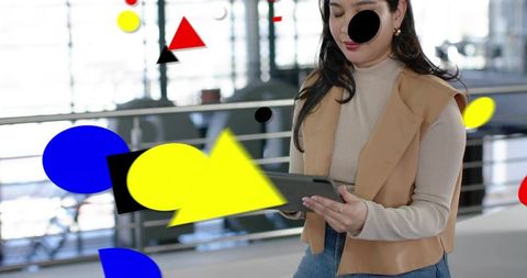 Young woman reading on tablet in modern atrium with colorful geometric overlays