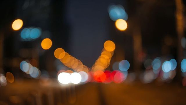 Nighttime urban bokeh with glowing headlights and taillights forming vanishing line