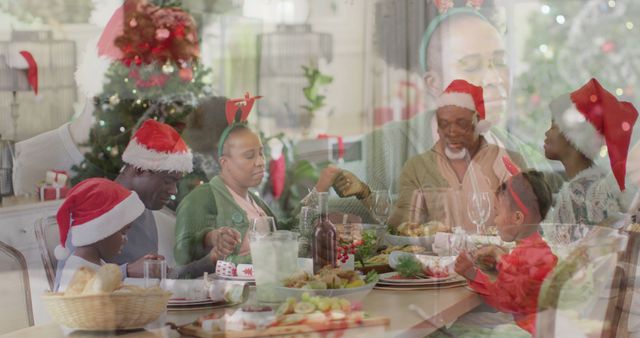 A family wearing Santa hats is gathered around a dinner table, enjoying a Christmas meal together. The table is adorned with a festive meal and decorations, while a decorated Christmas tree is visible in the background, adding to the holiday ambiance. Ideal for holiday greeting cards, promotional materials for Christmas events, and festive social media content.