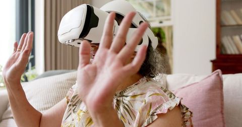 Senior woman using virtual reality headset at home