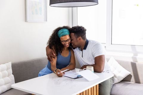 Young couple sharing affectionate moment while reviewing documents at bright breakfast nook