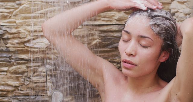 Woman standing under shower, washing hair with closed eyes. Perfect for promoting self-care routines, beauty and hygiene products, shower installations, relaxed lifestyle, spa experiences, and personal health.