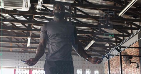 Bearded man jumping rope in industrial gym performing high-intensity cardio workout