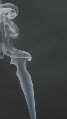 Vertical video of curling smoke plume forming abstract ethereal shapes on dark backdrop