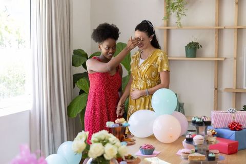 Two Female Friends Enjoying Celebration at Home With Balloons and Gifts