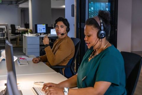 Multicultural team collaborating on customer support and analytics in modern open-plan office