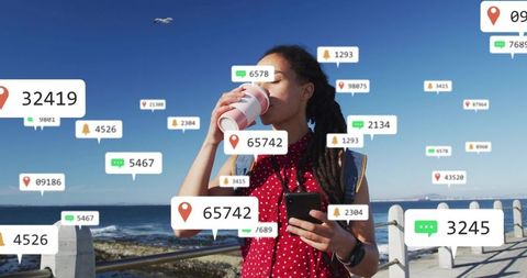Sipping coffee while checking phone on seaside promenade with social media alerts