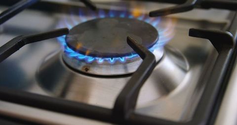 Close-Up of Blue Flames on Gas Stove Burner in Kitchen